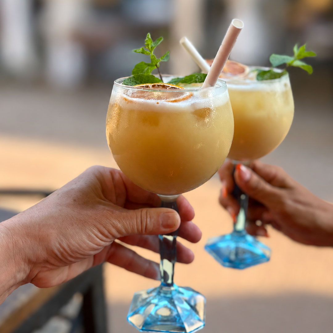 Vue sur deux mains en train de trinquer avec un cocktail chacun, le Yacht Café, bar Carnon.