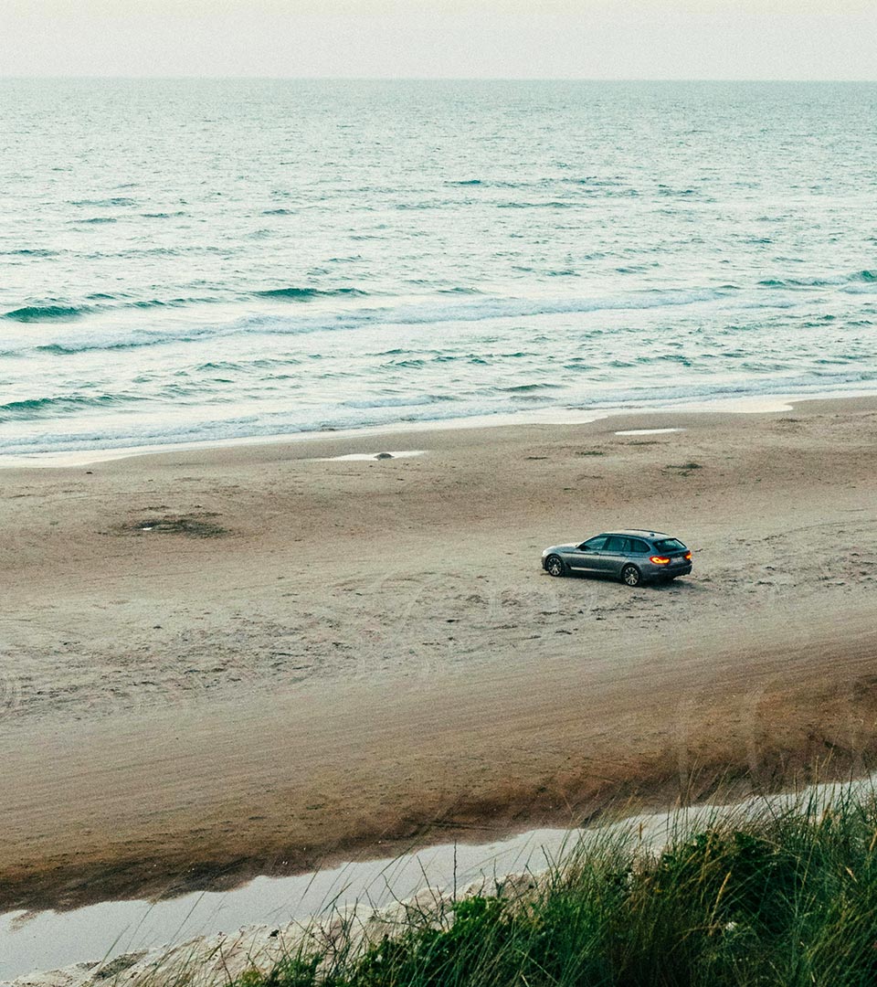 Vue d'une voiture sur une plage avec la mer pour illustrer le stationnement à Carnon, le Yacht Café, restaurant Carnon port.