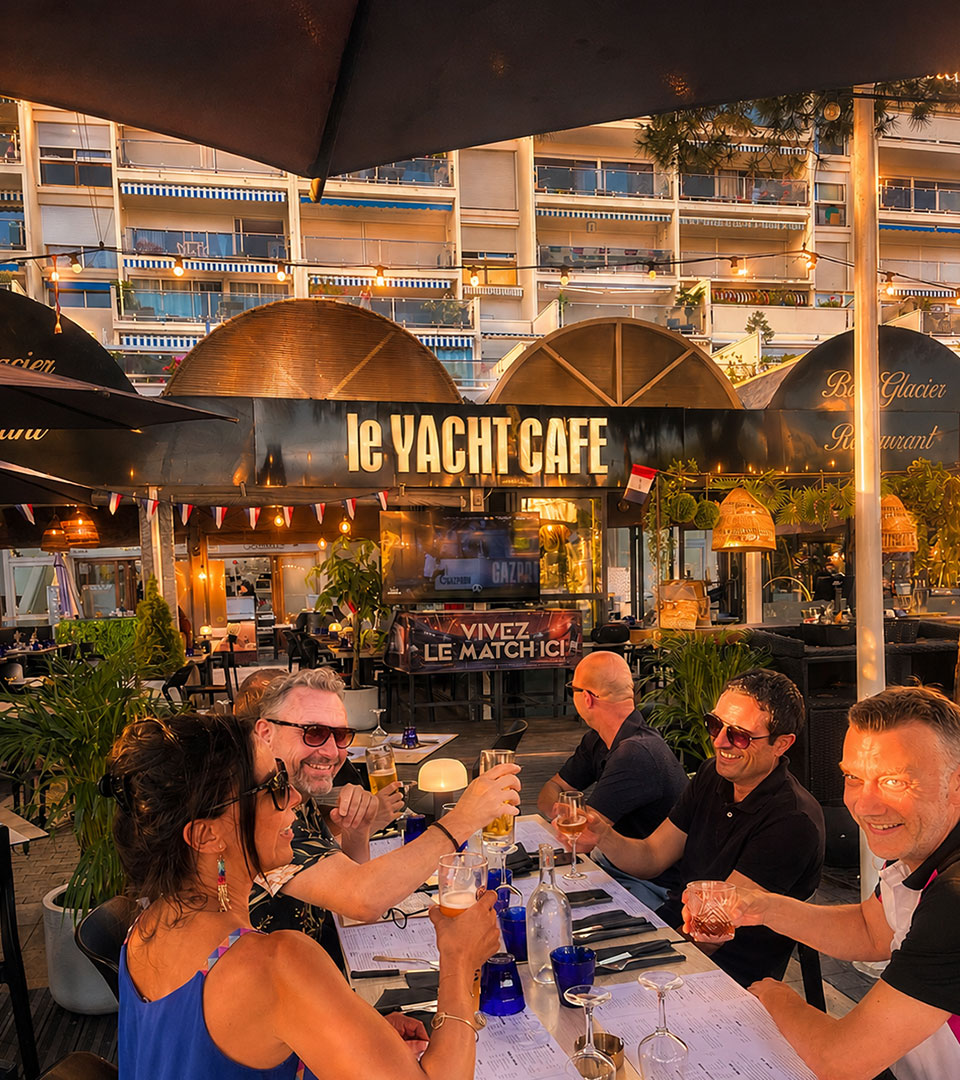 Vue sur la terrasse extérieure avec des clients face un match de foot, au Yacht Café, restaurant Carnon bord de mer.