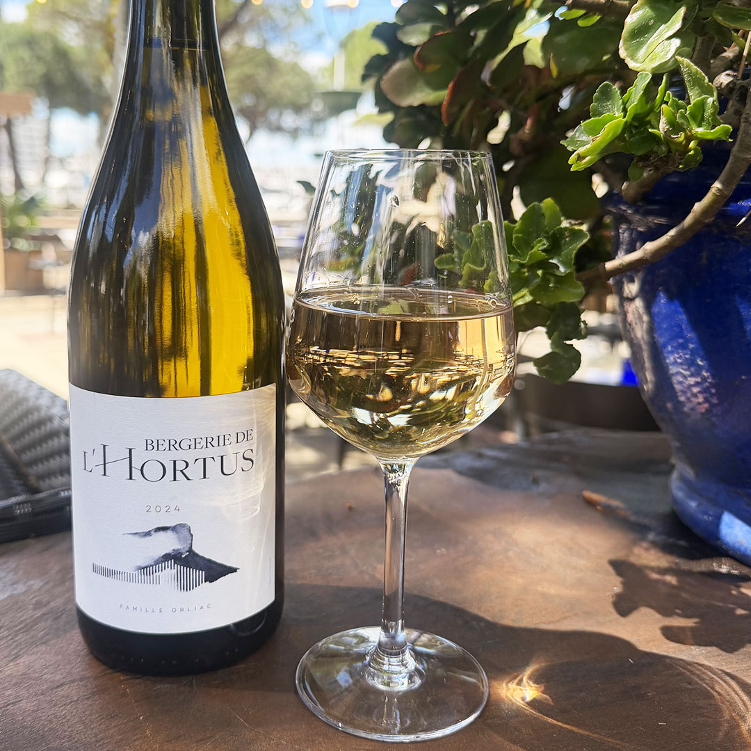Vue sur une bouteille de vin blanc de la Bergerie de l'Hortus sur une table extérieure du Yacht Café, bar Carnon.
